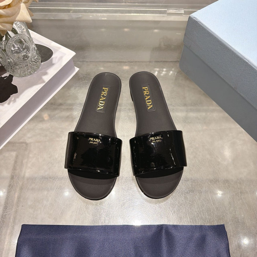 PRADA 26S LOGO EMBOSSED SLIDE SANDALS IN BLACK PATENT CALFSKIN