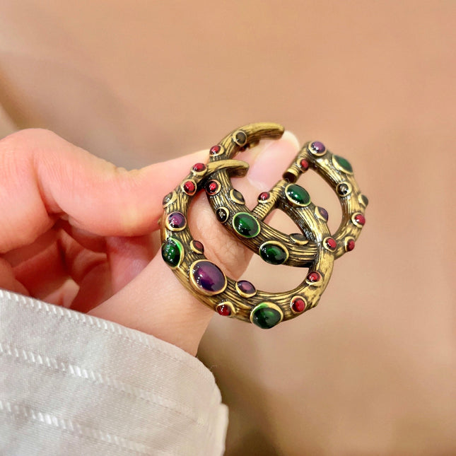 GUCCI 26S INTERLOCKING G MULTICOLOR GEM LOGO BROOCH IN ANTIQUE GOLD TONE METAL 625634