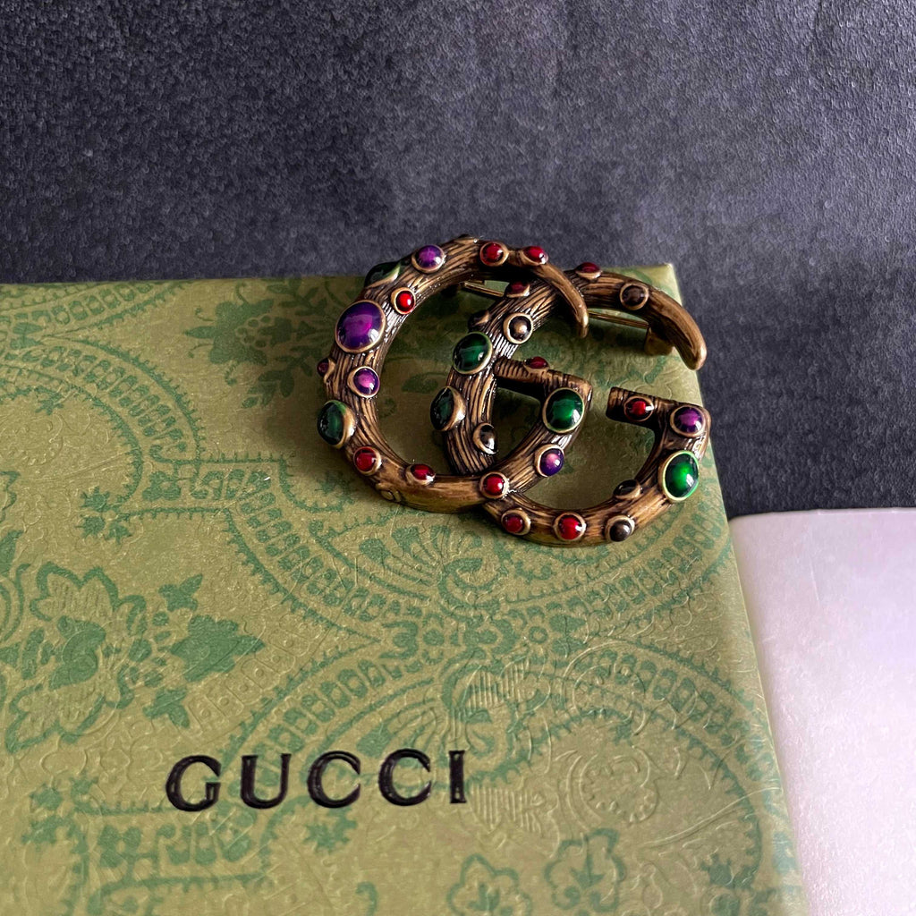 GUCCI 26S INTERLOCKING G MULTICOLOR GEM LOGO BROOCH IN ANTIQUE GOLD TONE METAL 625634